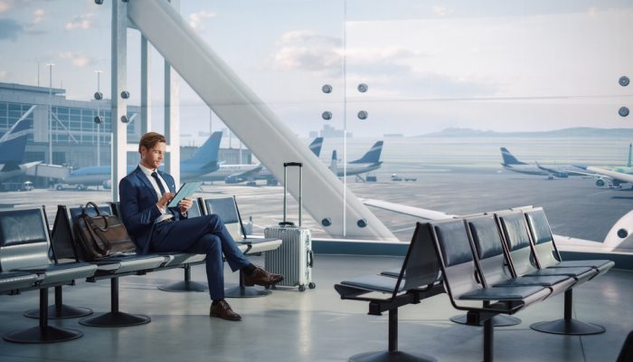 Airport,Terminal,Flight,Wait:,Smiling,Businessman,Uses,Digital,Tablet,Computer